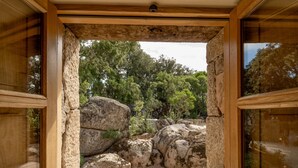Un portail encadré de pierres qui mène à un paysage naturel, avec de gros rochers et des arbres.