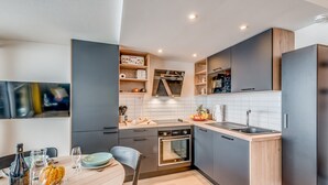 Eine moderne Küche mit grauen Schränken, einem Holzespeisetisch und einem eingebauten Backofen.