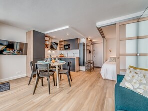 A compact living space with a dining area, kitchenette, and a bedroom.