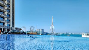 En swimmingpool med fri utsikt över en modern byggnad och ett pariserhjul i bakgrunden.
