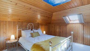 A wooden-paneled bedroom with a bed, bedside lamps, and a skylight. - Melody House of Ponta do Sol (Ponta do Sol)