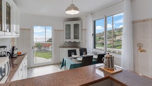 A kitchen with a dining area, large windows, and a view of the outdoors. - Melody House of Ponta do Sol (Ponta do Sol)