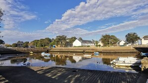 A calm river with boats docked, a bridge, and buildings along the riverbank. - Carnac: 3-room Duplex, 4 pers, Close to beach, Wifi (Carnac)