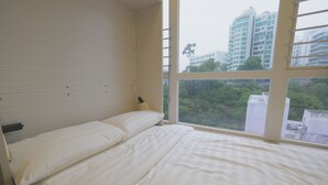 A bedroom with a bed, a window, and a view of buildings and greenery. - China Rich Hotel (Hong Kong)