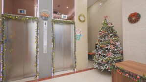 An elevator area with a Christmas tree and holiday decorations. - China Rich Hotel (Hong Kong)