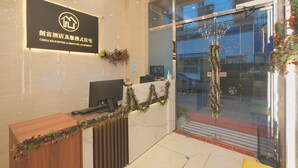 A reception desk with a sign for China Rich Hotel & Serviced Apartment, a computer, and a telephone. - China Rich Hotel (Hong Kong)