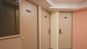A hallway with three wooden doors, each with a nameplate. - China Rich Hotel (Hong Kong)