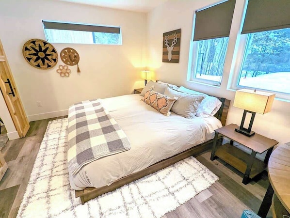 Un dormitorio con cama, mesitas de noche, alfombra y adornos en la pared.