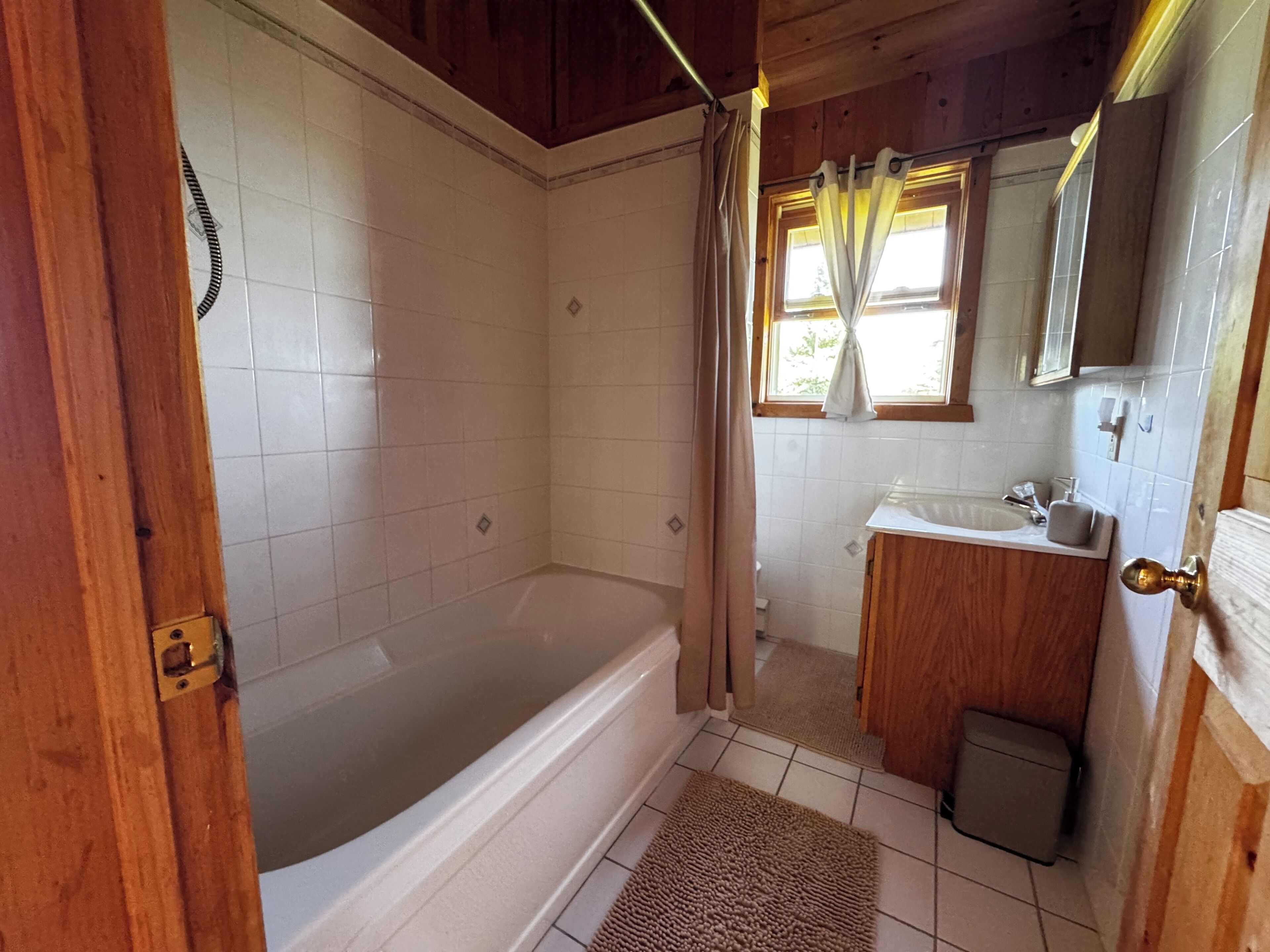 A bathroom with a bathtub, a sink, and a mirror.