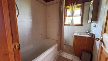 A bathroom with a bathtub, a sink, and a mirror.