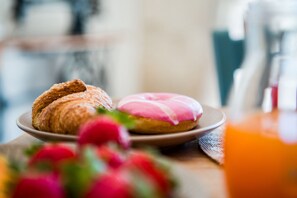 A plate with a croissant and a pink frosted donut on a table. - Trulli Nuova Aia Resort (Martina Franca)