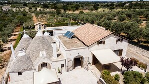 Un edificio tradicional de piedra con techo de tejas, un patio cubierto y un panel solar.
