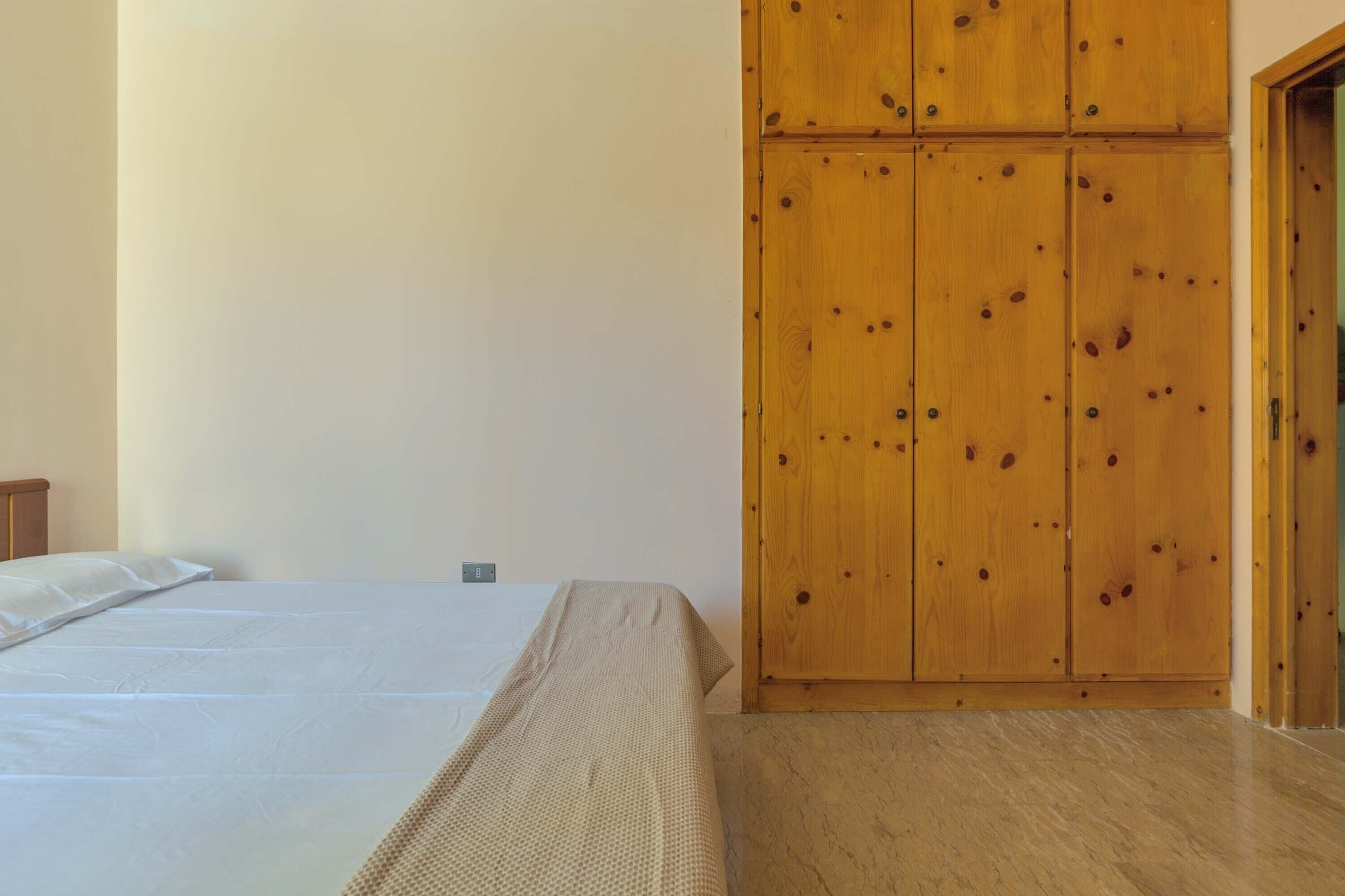 Une chambre à coucher avec un lit, une armoire en bois et une porte.
