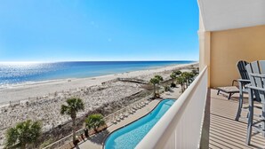 Een balkon met uitzicht op een strand en een zwembad.