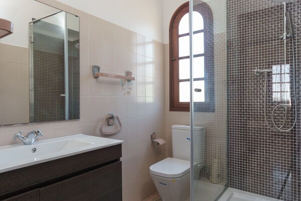 A bathroom with a glass-enclosed shower, a white sink, and a toilet.