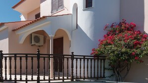 A building with a balcony, a door, and a tree with red flowers. - Costa Red Villa, Quarteira, Algarve (Semino)