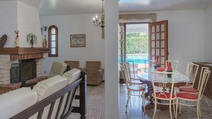A living room with a fireplace, seating, and a dining area with a table and chairs. - Costa Red Villa, Quarteira, Algarve (Semino)