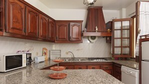 A kitchen with granite countertops, wooden cabinets, a microwave, a coffee maker, and a dishwasher. - Costa Red Villa, Quarteira, Algarve (Semino)
