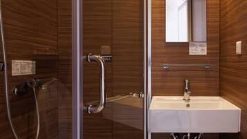 A modern bathroom with a glass shower enclosure, a sink with a mirror above it, and wooden paneling on the walls.