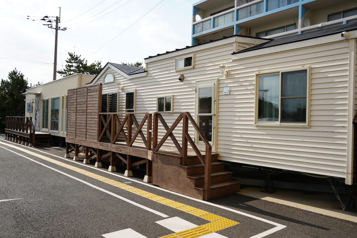 A row of mobile homes with a wooden deck and steps leading to the entrance.
