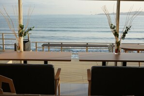 Un restaurante frente al mar, con mesas y sillas de madera.