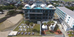 Un hotel moderno con piscina en la azotea, varios pisos y ubicación frente a la playa.