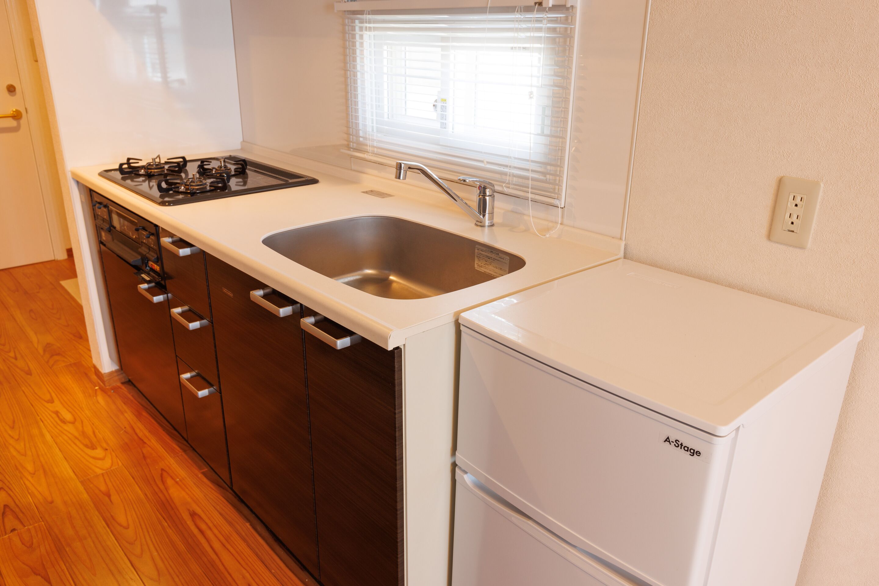 A compact kitchen with a gas stove, sink, and a white refrigerator.