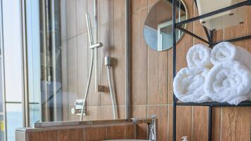 A modern bathroom with a wooden vanity, a white sink, a mirror, and a towel rack.