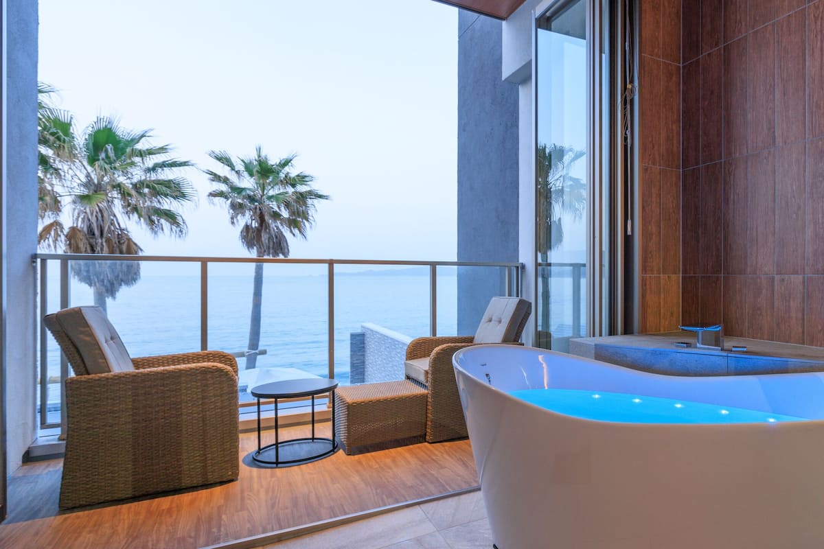 A modern bathroom with a freestanding bathtub, a small table, and wicker chairs.