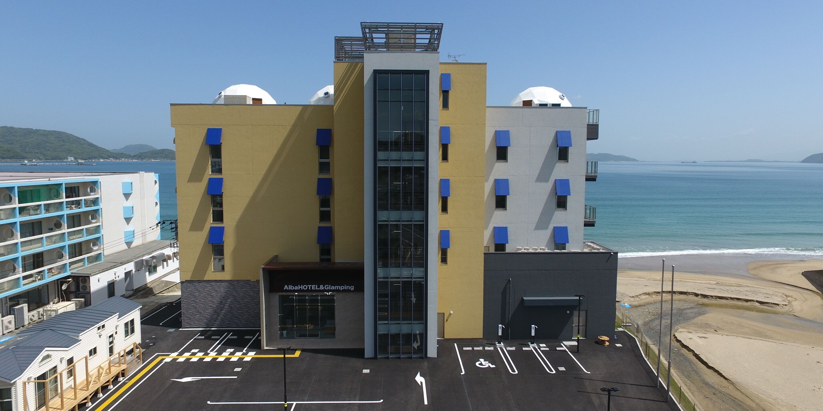 A hotel with a modern design, featuring a central glass facade and multiple balconies.