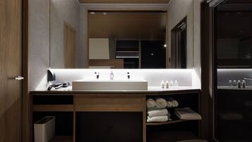 A modern bathroom with a large mirror, a white sink, and built-in towel storage.