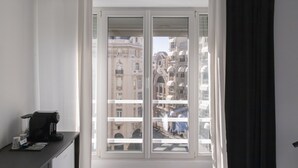 Une pièce dotée d’une grande fenêtre, d’une machine à café et offrant une vue sur les bâtiments environnants.