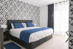 Une chambre à coucher moderne avec un grand lit, une tête de lit sombre et un papier peint à motifs.
