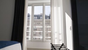 Une chambre d’hôtel avec une grande fenêtre, un lit et une chaise.