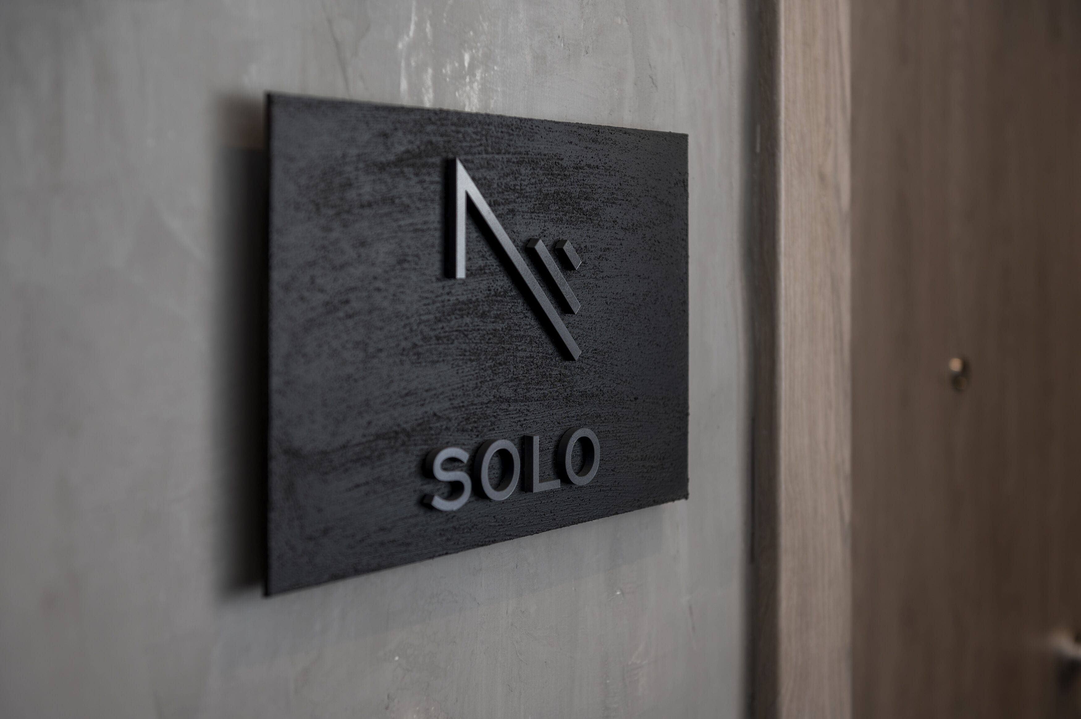 Ein schwarzes Schild mit den Aufschriften „N“ und „SOLO“ an einer Wand befestigt.