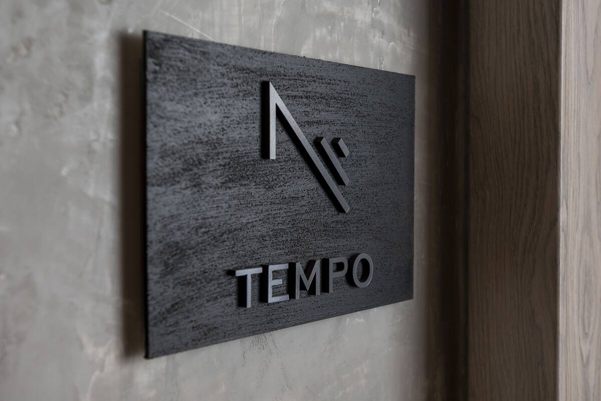 Een zwart bord met een gestileerde 'N' en het woord 'TEMPO' in hoofdletters.