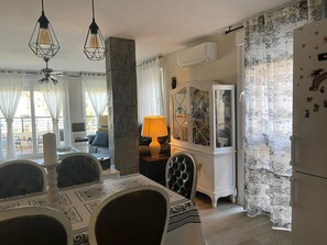 A dining area with a table set for four, a chandelier, a cabinet with glass doors, and a refrigerator.