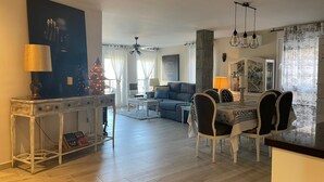 Un salon moderne avec un coin repas, un grand tableau au mur et un sapin de Noël.