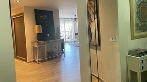 Une pièce avec un plancher en bois, une cloison en verre, un bureau avec une lampe et un tableau encadré au mur.