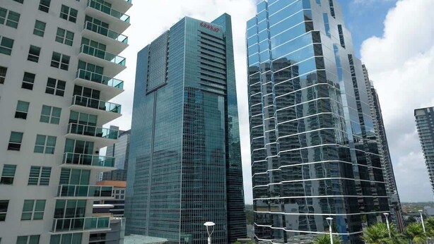 A modern high-rise building with a glass facade and a prominent logo on the top. - 2BR Heart of Brickell W/ Pool, Hot Tub, and Gym! (Miami)