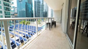 A balcony with a view of modern buildings, a railing, and a few chairs. - 2BR Heart of Brickell W/ Pool, Hot Tub, and Gym! (Miami)