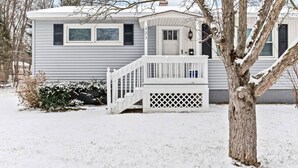 A single-story mobile home with a white exterior, a front porch with a railing, and a small front yard. - Boho Chic Work Escape - 2-Bedroom, Close to Burlington/Airport (South Burlington)