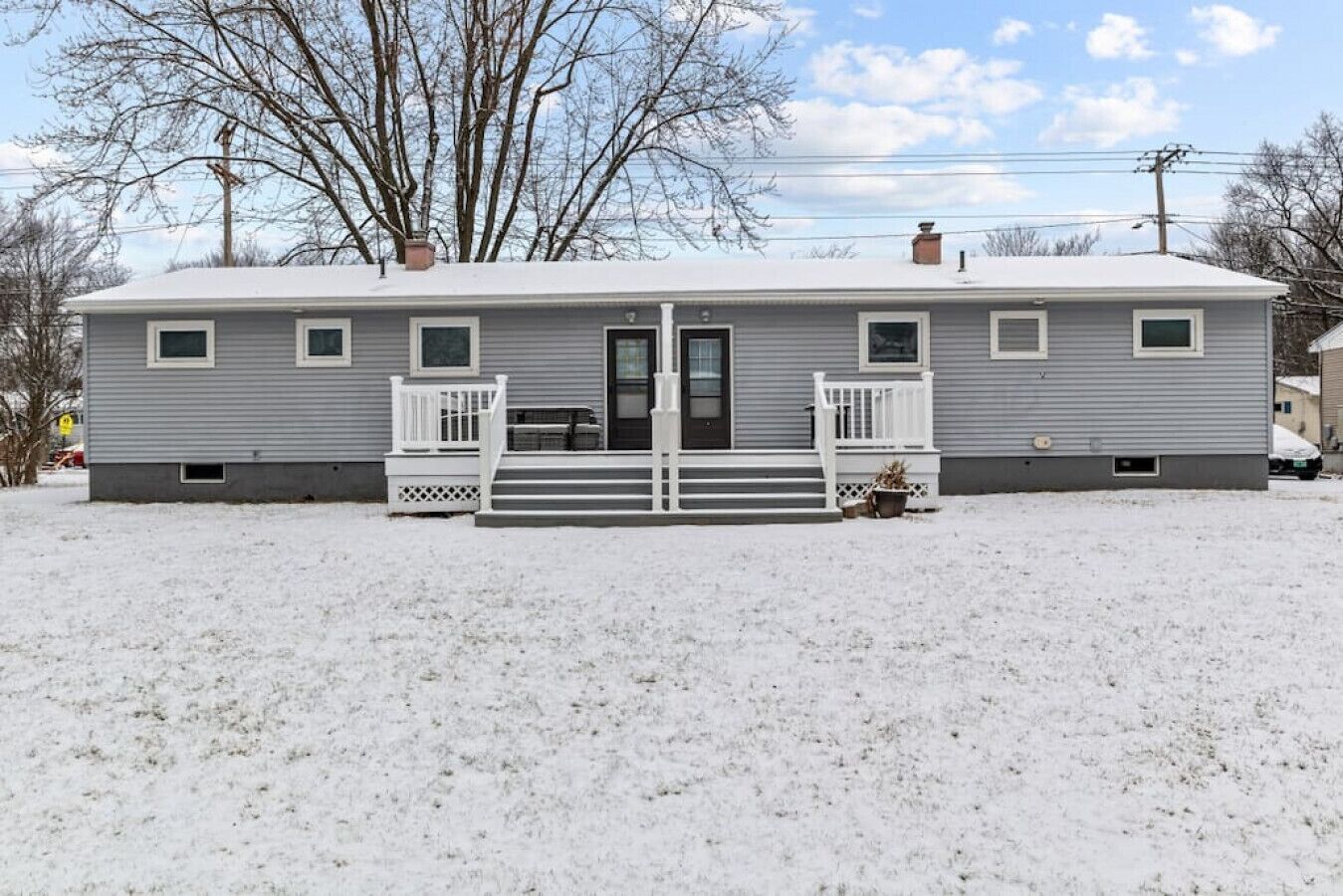 A single-story house with a front porch and a door, surrounded by snow.