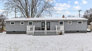 A single-story house with a front porch and a door, surrounded by snow. - Boho Chic Work Escape - 2-Bedroom, Close to Burlington/Airport (South Burlington)