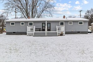 A single-story house with a front porch and a door, surrounded by snow. - Boho Chic Work Escape - 2-Bedroom, Close to Burlington/Airport (South Burlington)