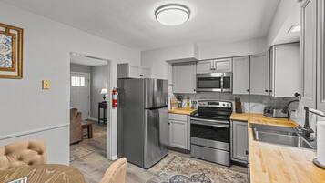 A modern kitchen with stainless steel appliances, a wooden countertop, and a patterned rug.
