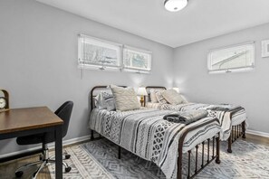 Un dormitorio con cama, mesitas de noche, escritorio y silla.
