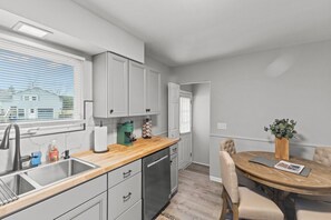A modern kitchen with grey cabinets, a wooden countertop, and a built-in dishwasher. - Boho Chic Work Escape - 2-Bedroom, Close to Burlington/Airport (South Burlington)