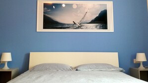 A bedroom with a bed, two bedside tables with lamps, and a framed picture of a sailboat on the wall. - Flat with terrace, quiet and sunny,2 bike, air cond,bike storage (Riva del Garda)