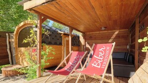 Une cabane en bois avec deux fauteuils rouges, portant l’inscription « Biber FERIENHOF », et une petite terrasse en bois.